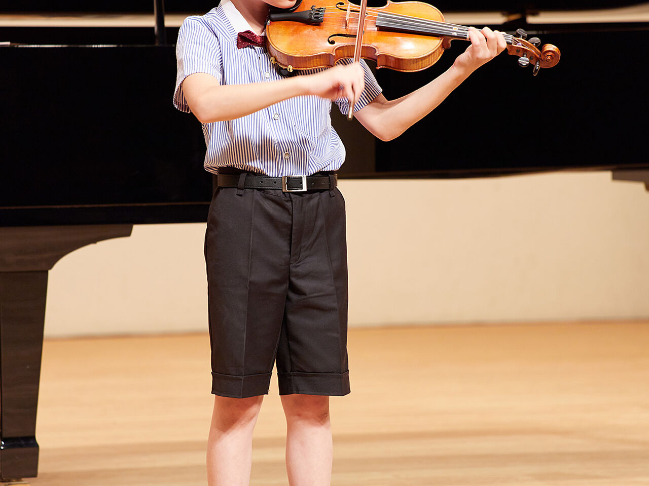 発表会でバイオリンを弾いている男の子の画像