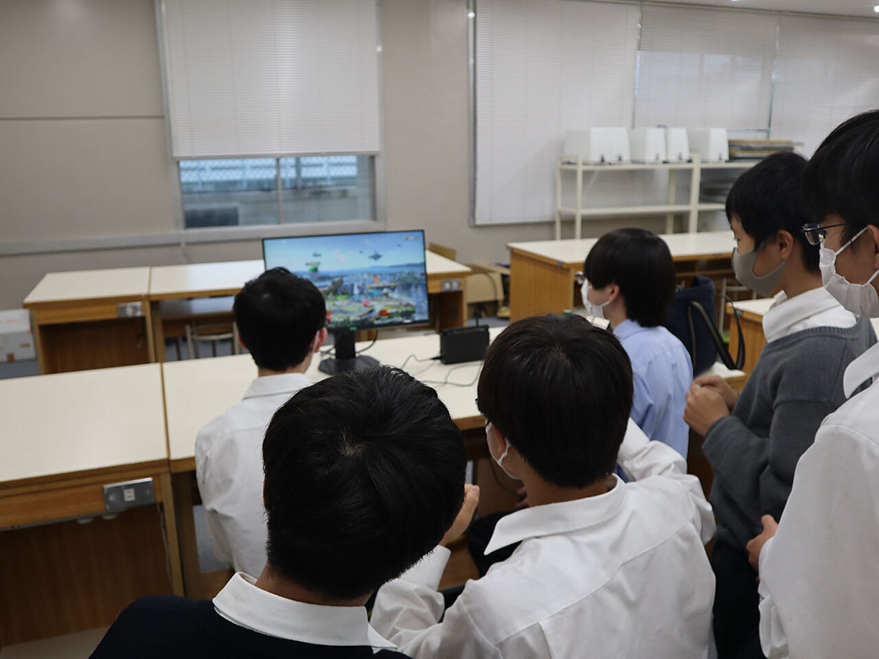 男子生徒たちがひとつのパソコンを囲んでゲームを見ている画像