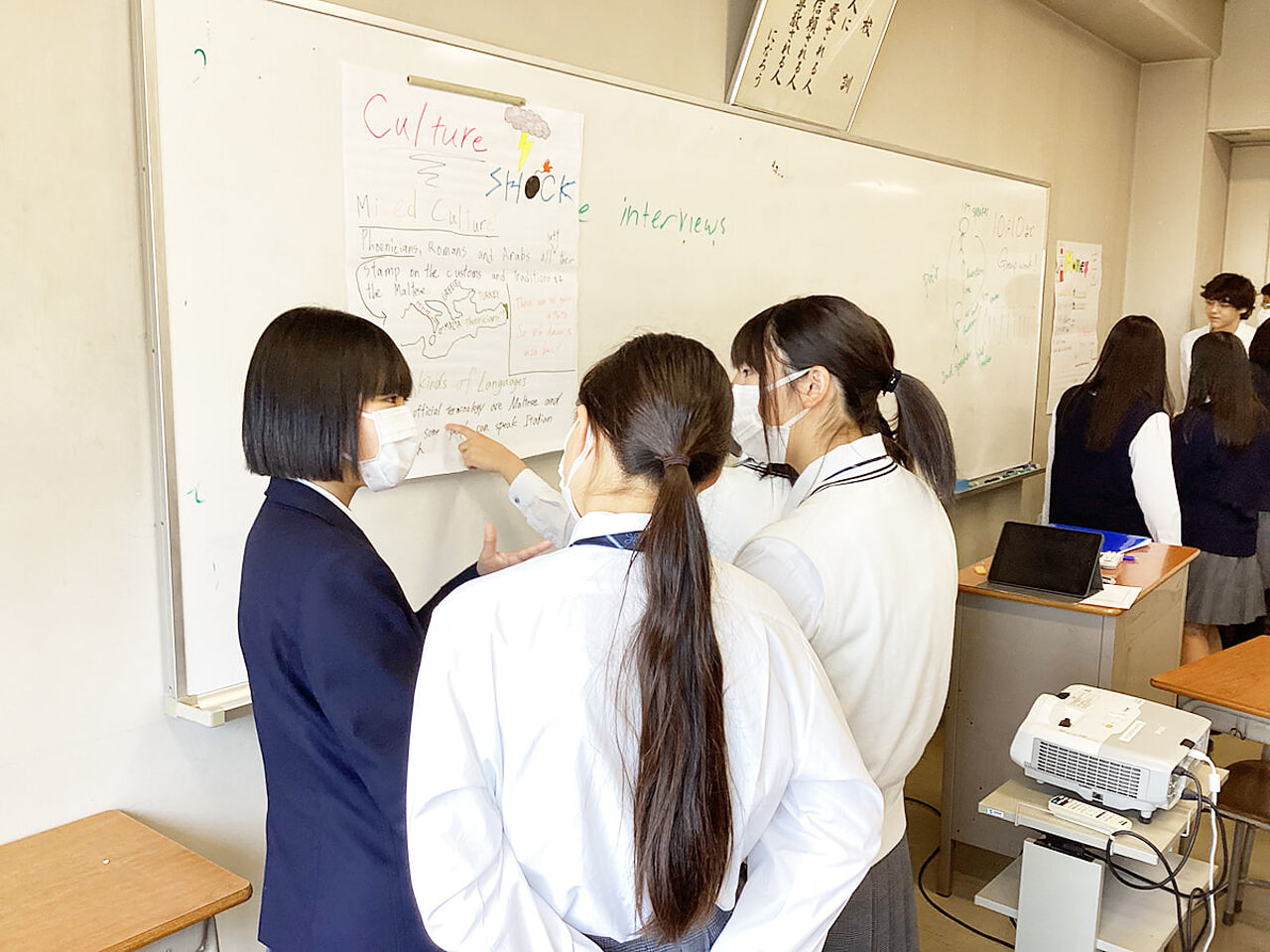 女子生徒3人がホワイトボードの前で英語を学習している画像