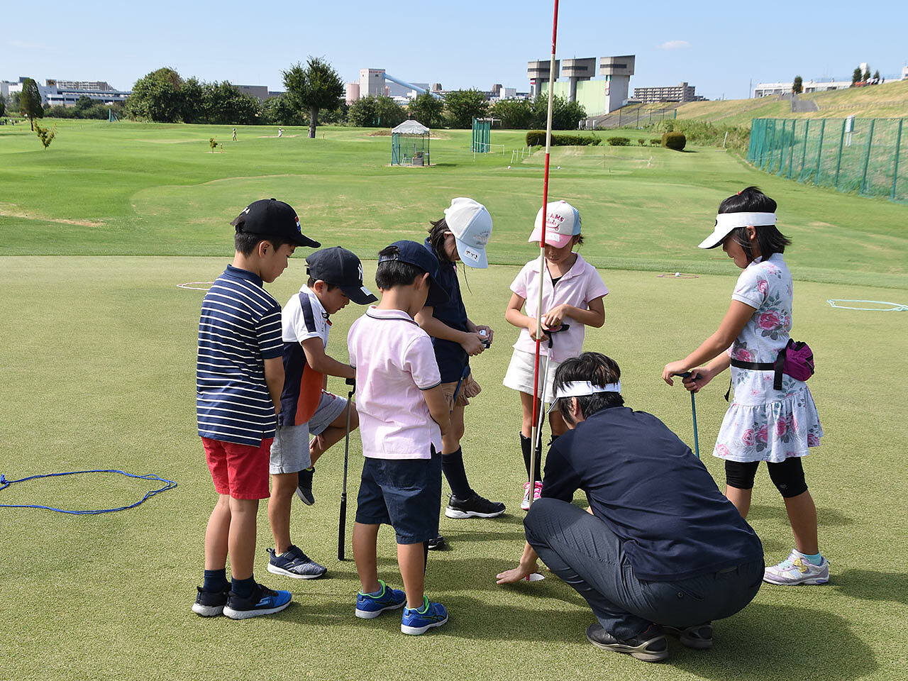 子どもたちがコースに出てゴルフの指導を受けている画像