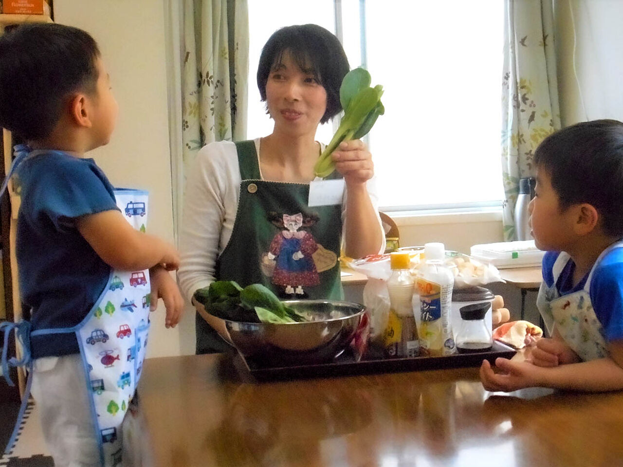 田中さんが子どもたちに野菜を見せながら説明している様子が分かる画像