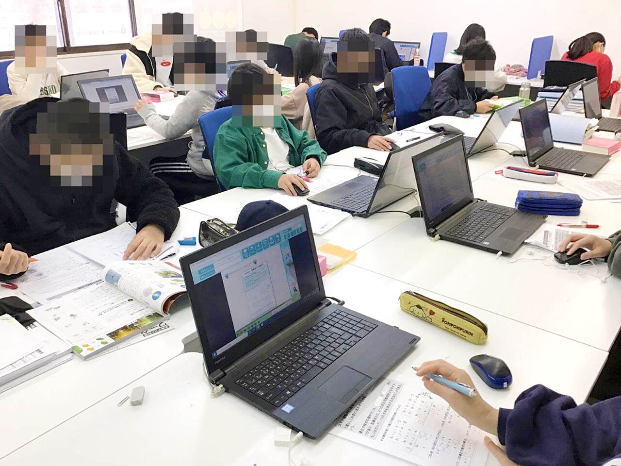 子どもたちがパソコンや教科書を見て勉強している画像