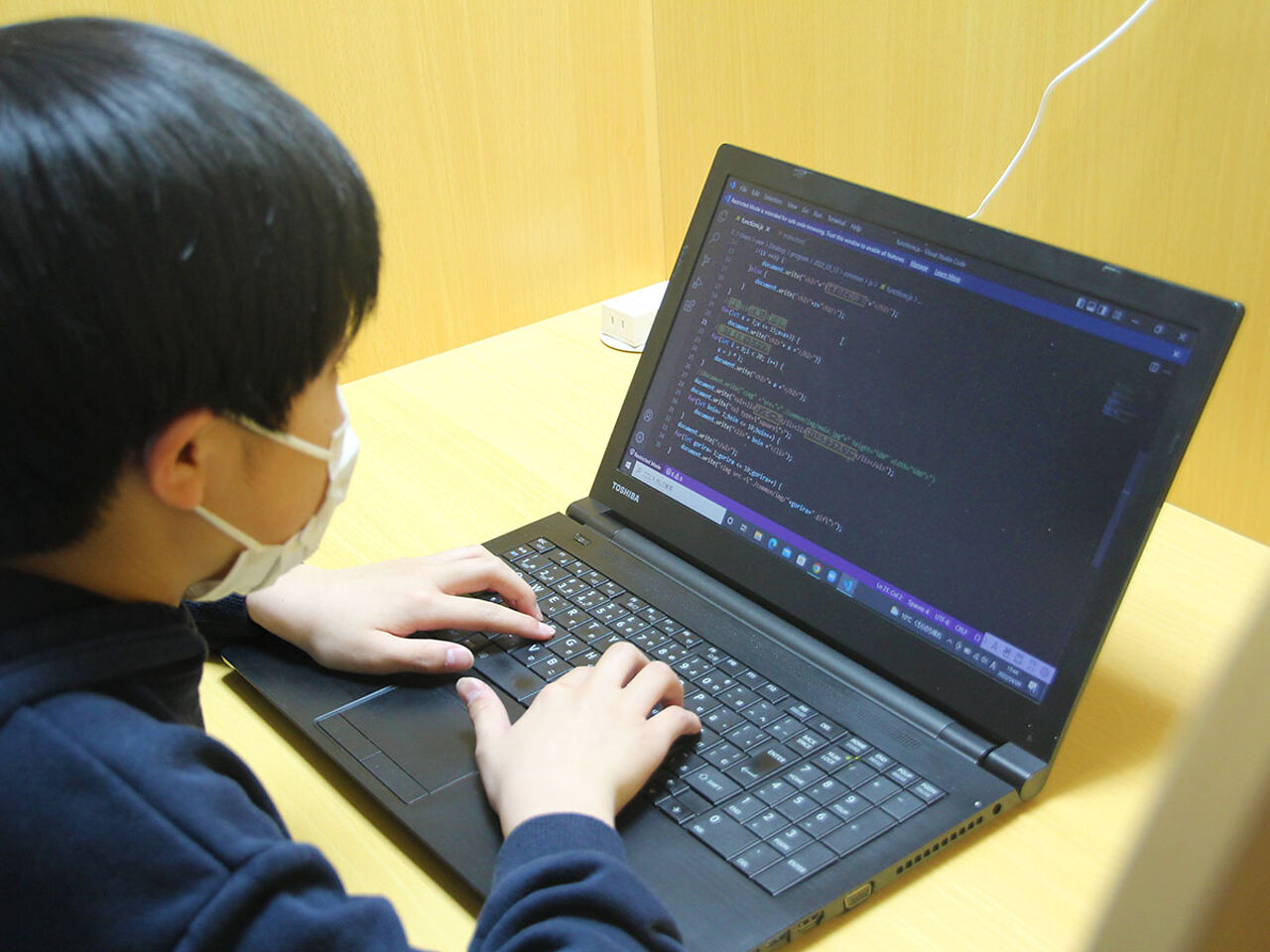 男の子がPCでプログラミングを打っている画像