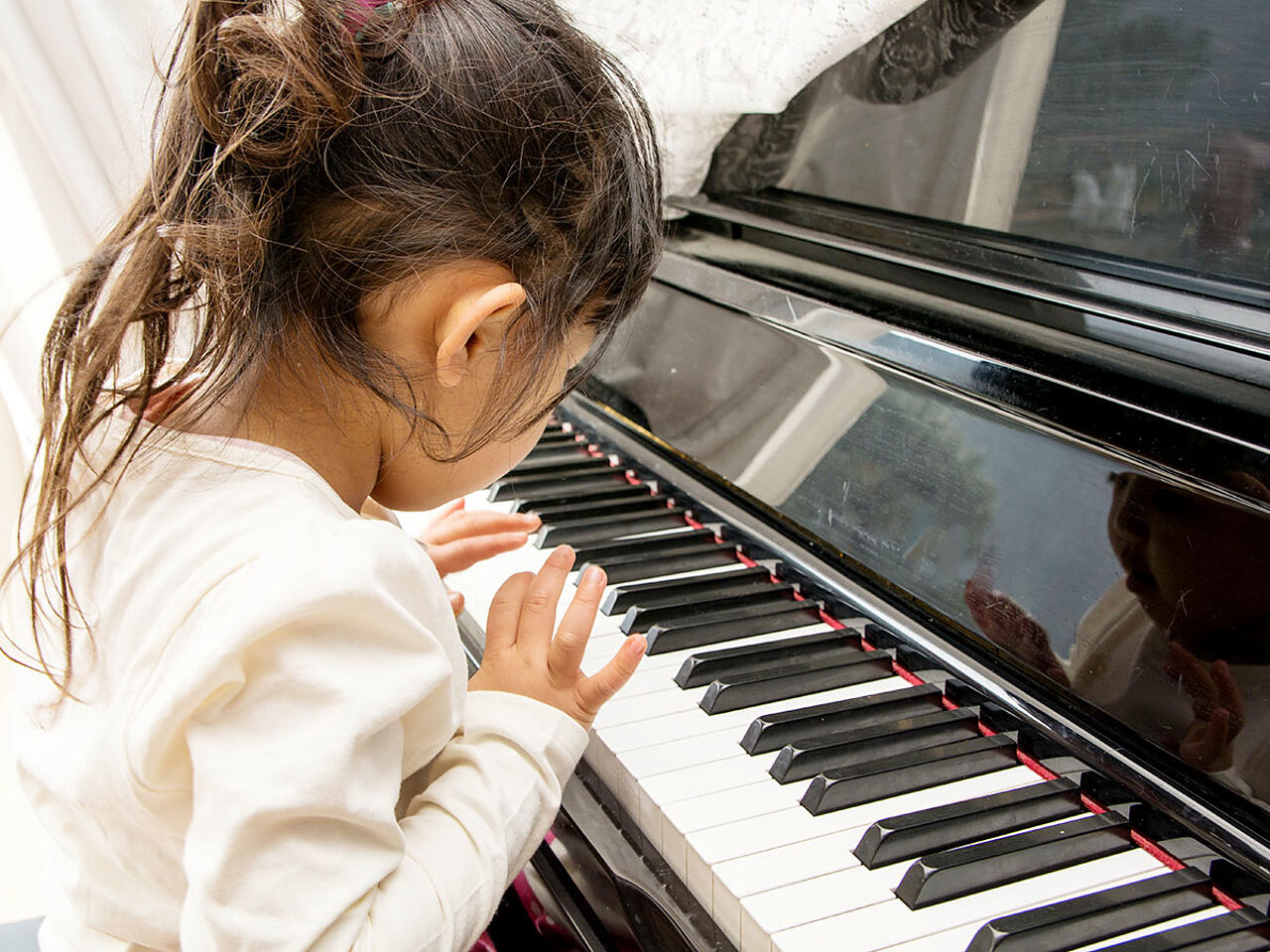 女の子が両手でピアノを弾いている画像