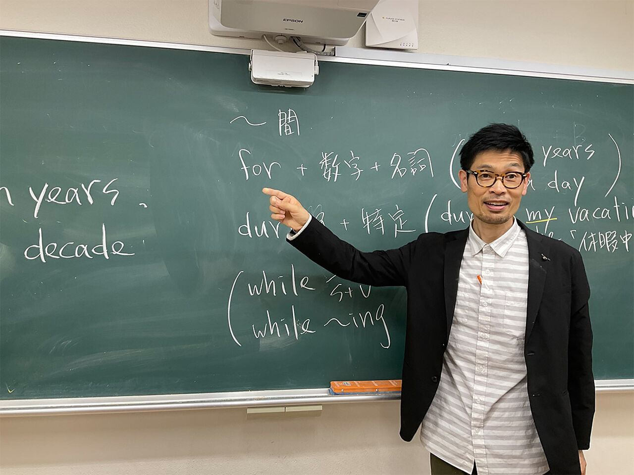 松田さんが黒板の前で授業をしている画像