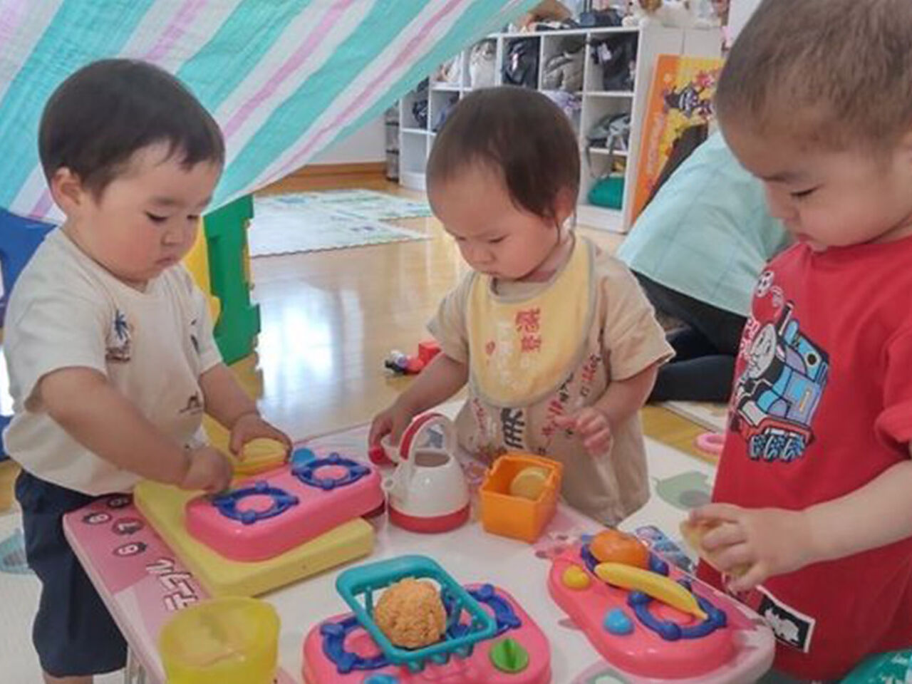 幼児3人が教室でおままごとをして遊んでいる画像