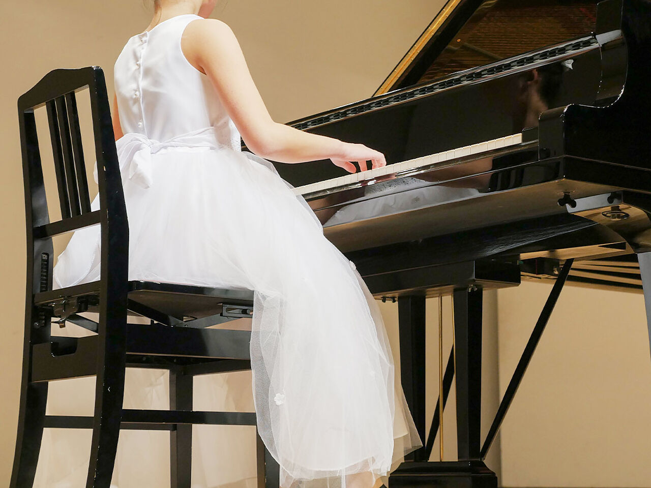 発表会で女の子がドレスを着てピアノを弾いている画像