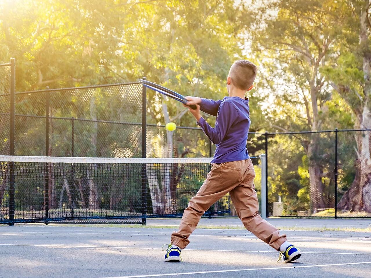 男の子が外でテニスをしている画像