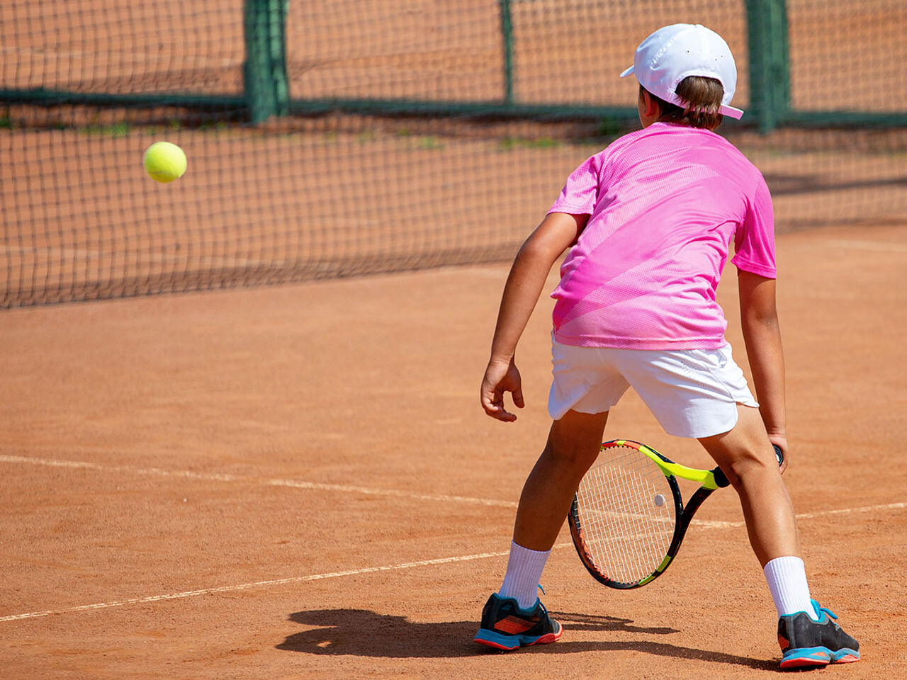 ピンクのウェアを着ている男の子がテニスをしている画像