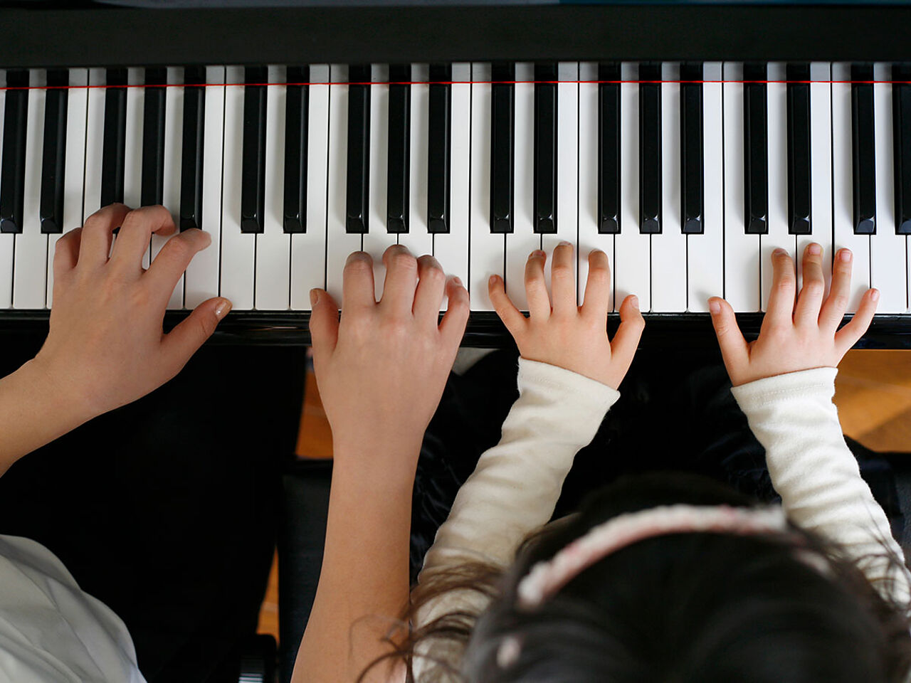大人と子どもがピアノを弾いている手のアップ画像