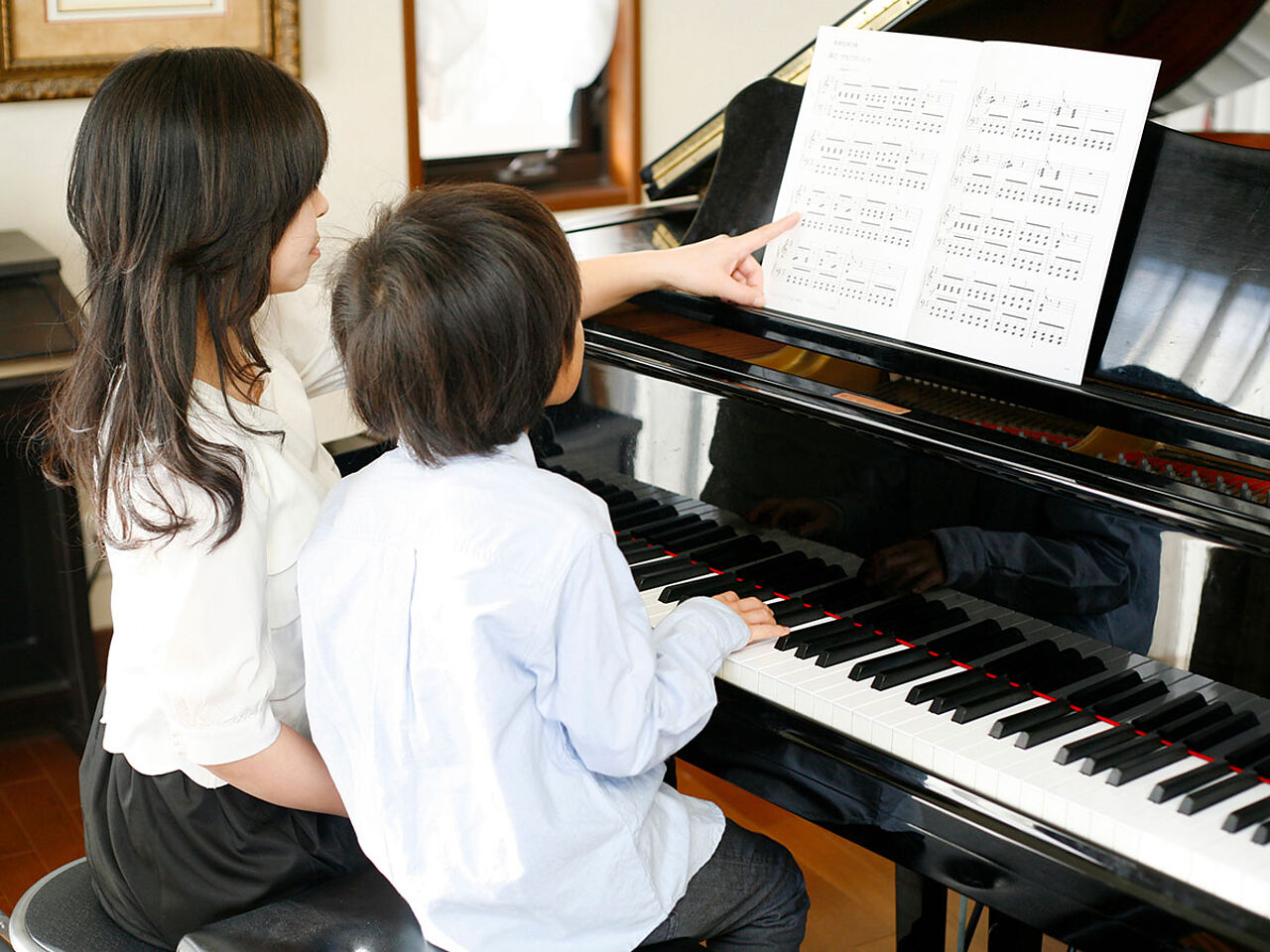 男の子が先生にピアノの指導を受けている画像