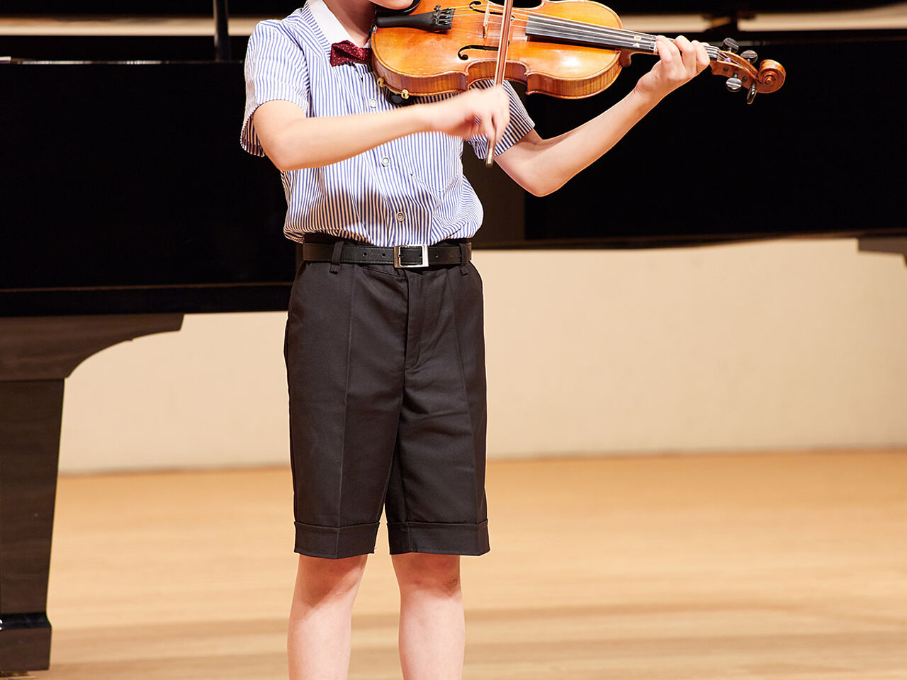 男の子が発表会でバイオリンを弾いている画像
