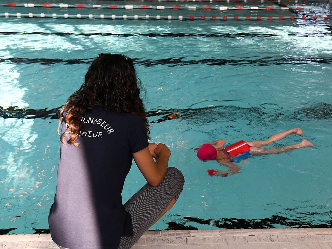 コーチが子どもに泳ぎの指導をしている画像