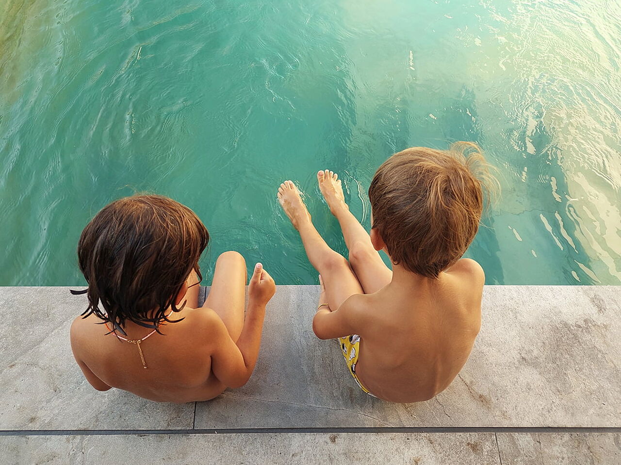 男の子2人がプールに足を入れて座っている画像
