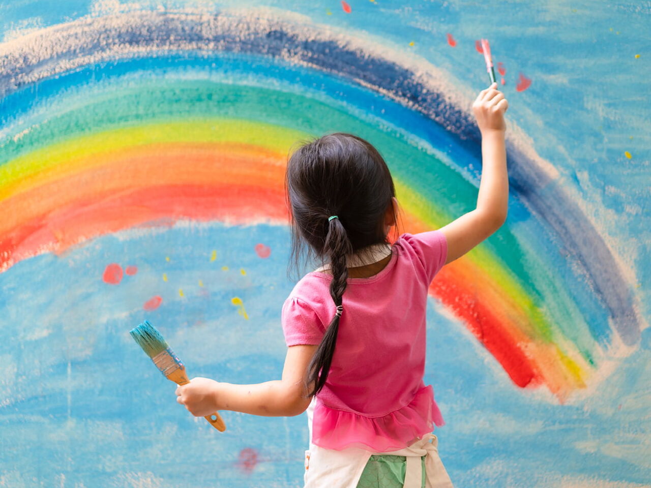 女の子が虹の絵を描いている画像
