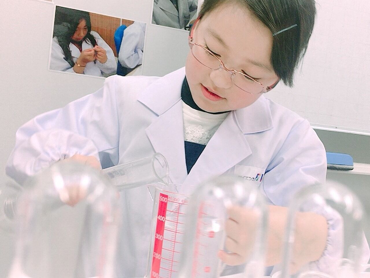 女の子がコップを持って理科の実験をしている画像