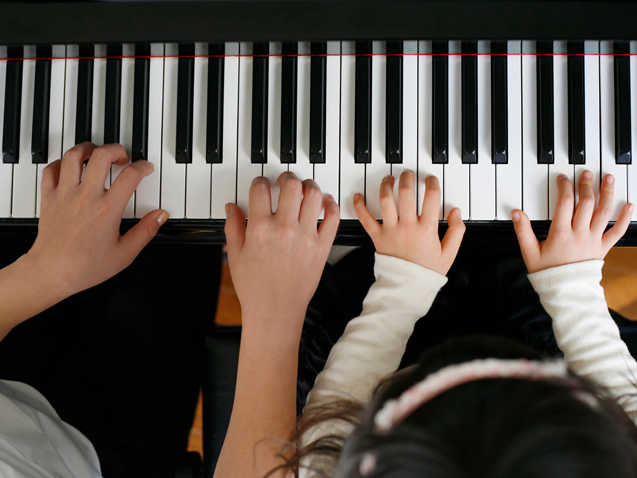 大人と子どもがピアノを弾いている手のアップ画像