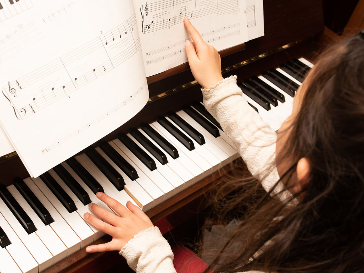 子どもが楽譜を見ながらピアノを弾いている画像