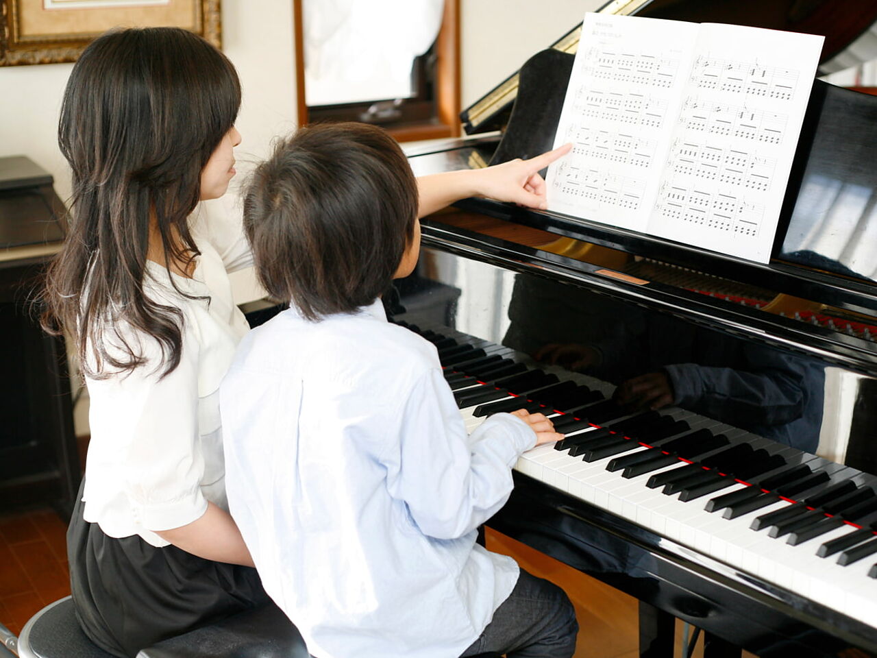 子どもが先生にピアノを教わっている画像