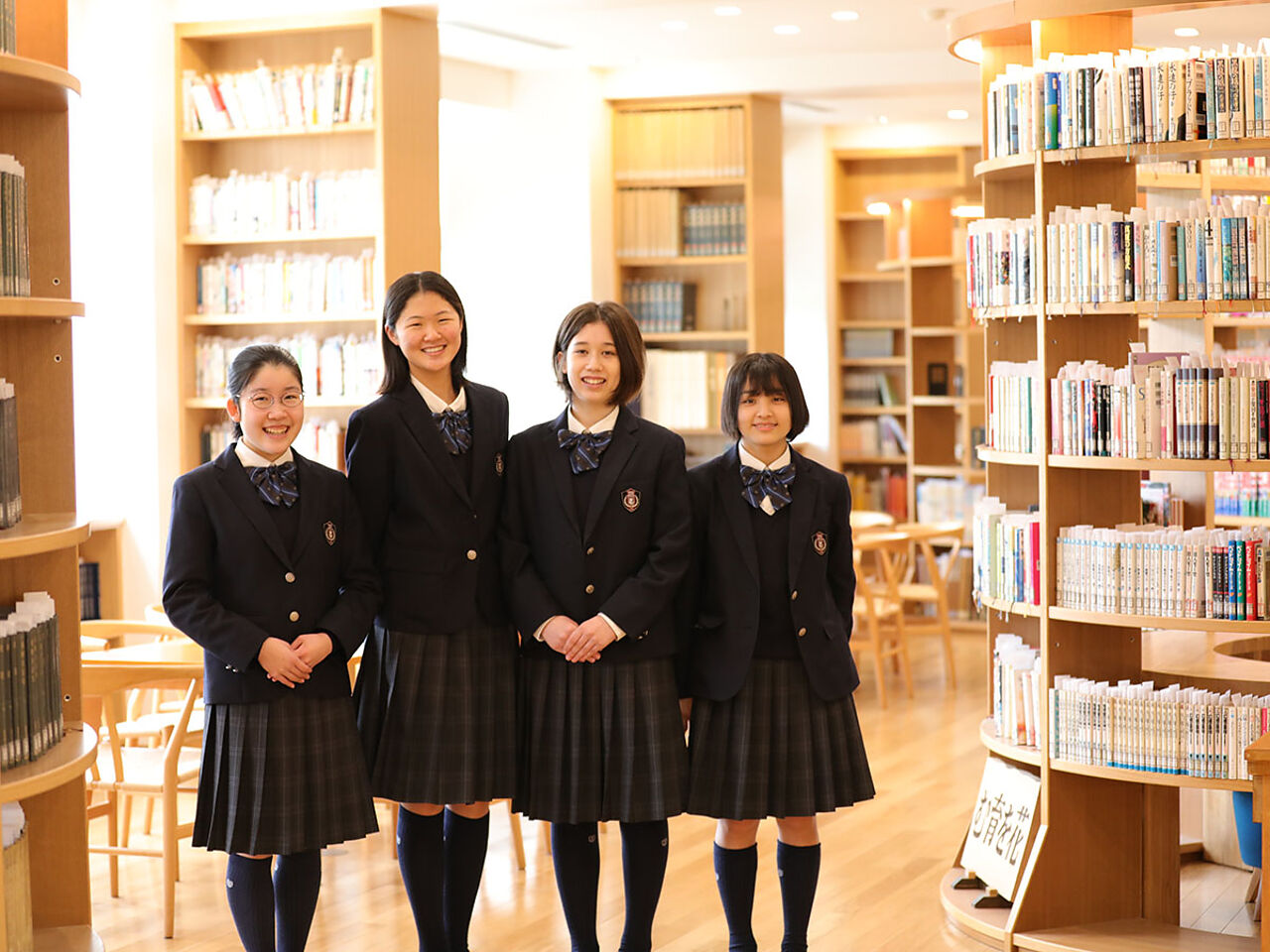 女子生徒が図書館で笑顔で並んでいる画像