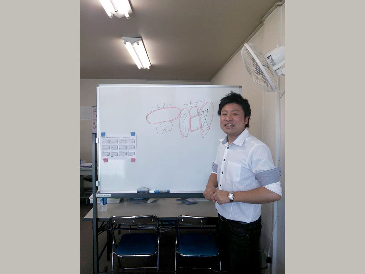 田中さんがホワイトボードの前で指導している画像