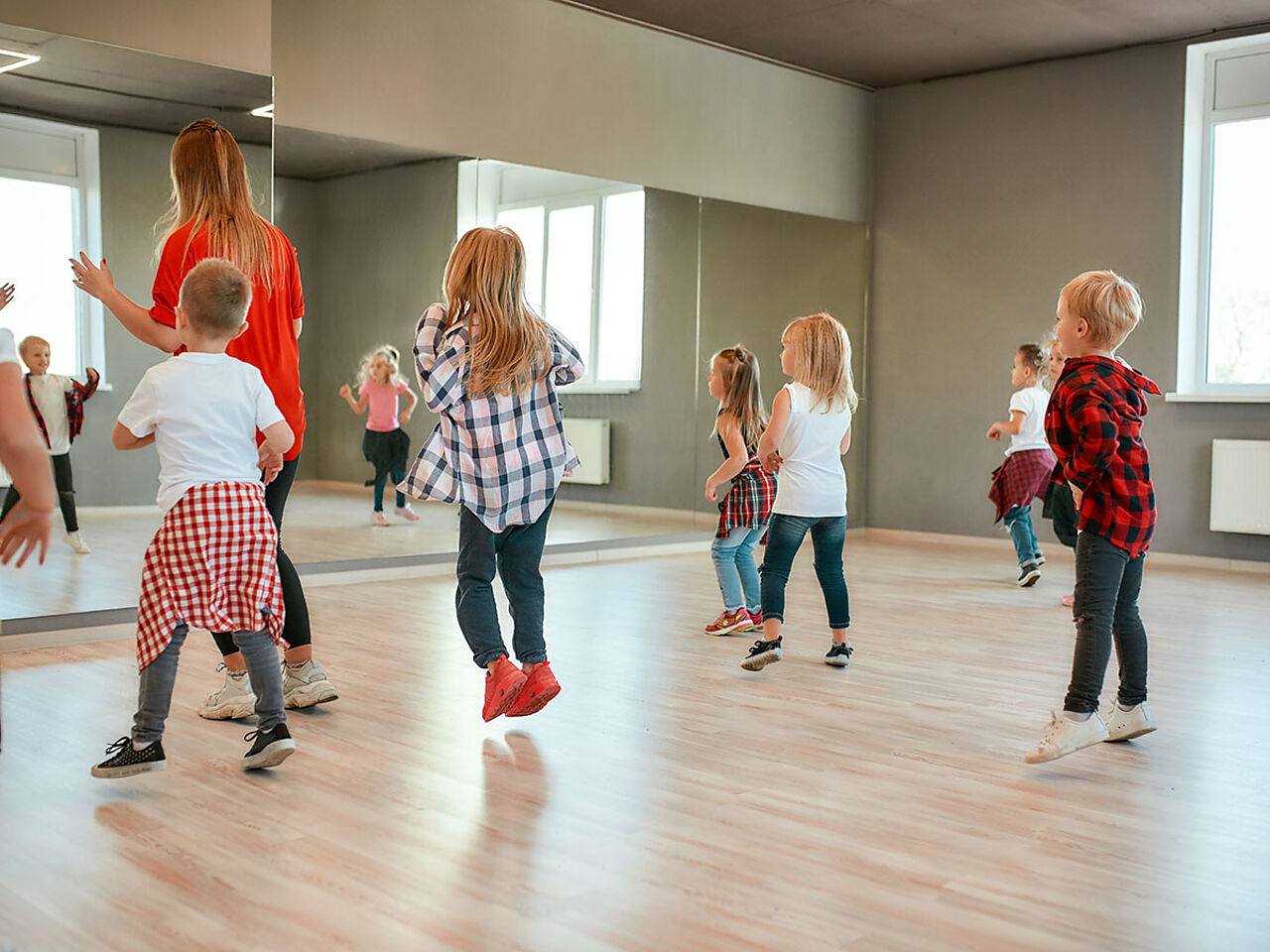 講師の後ろでダンスの練習をしている小さい子どもたちの画像