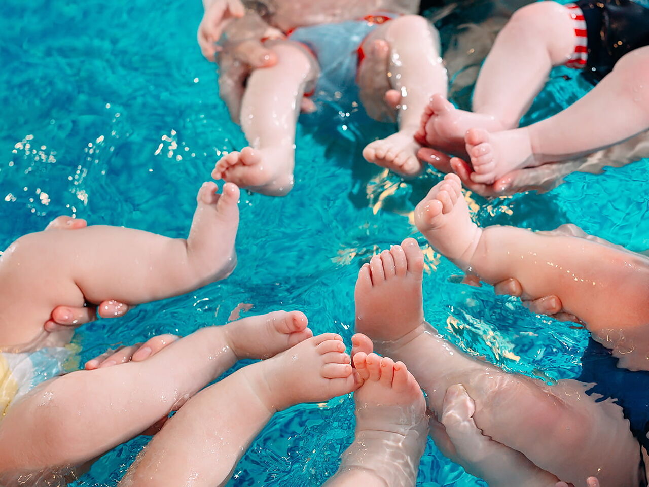 プールに浮かしている幼児たちの足のアップ画像