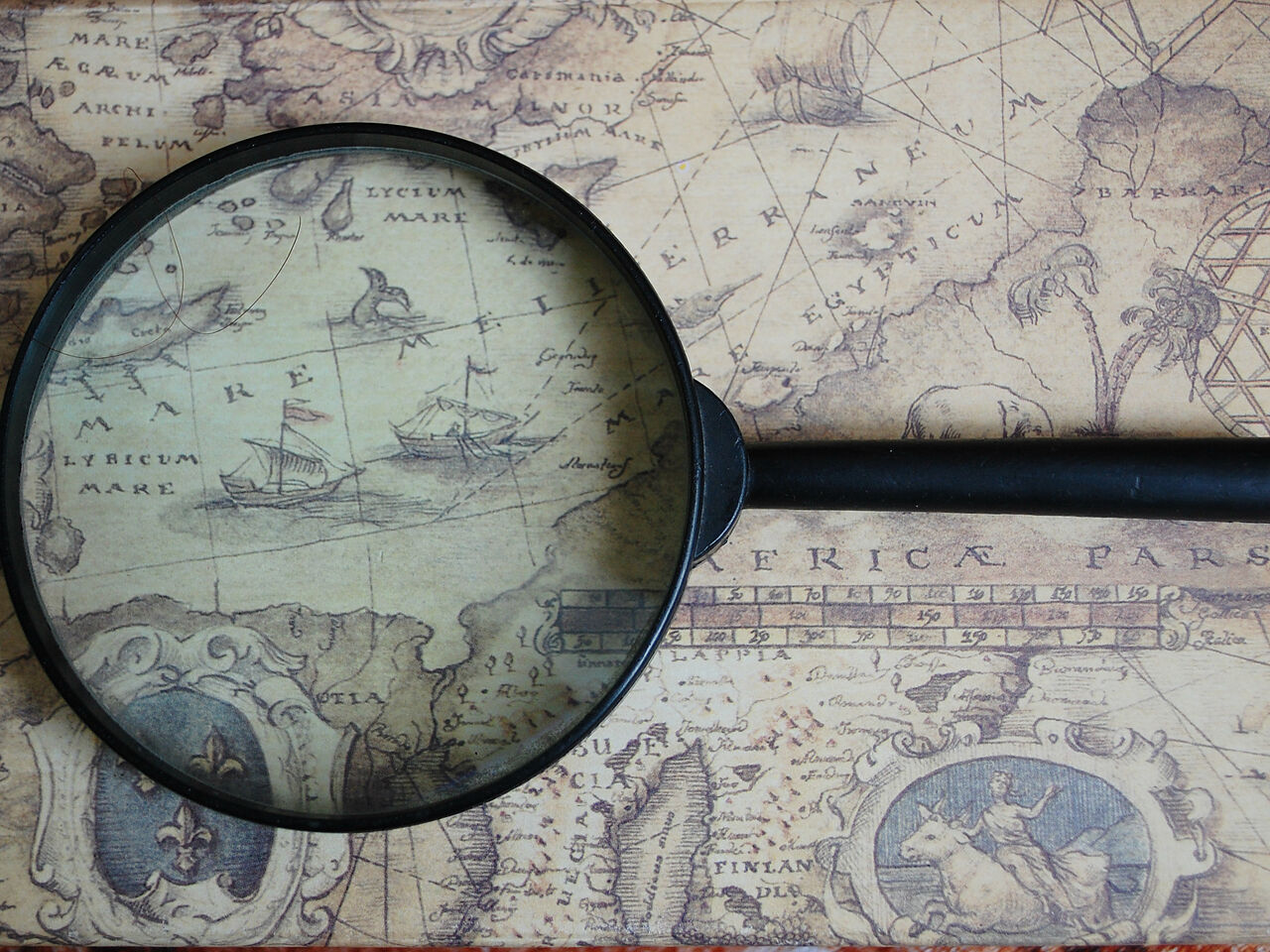 昔の世界地図に虫眼鏡が置いてある画像