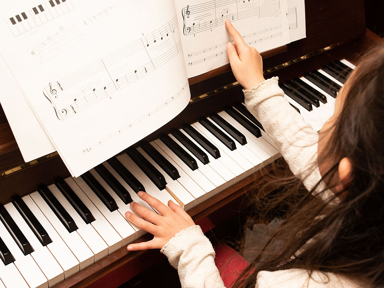 楽譜を見ながらピアノを弾く女の子の画像